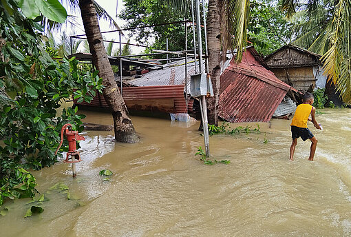 In der Provinz Occidental Mindoro, Region MIMAROPA, haben die Flut- und Windschäden Häuser und Lebensgrundlagen zerstört Ein Junge steht in überschwemmtem Gebiet neben einem zerstörten Haus