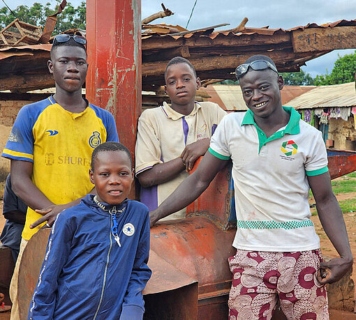 Vier Männer in Afrika stehen vor einer Werkstatt für Metallarbeiten