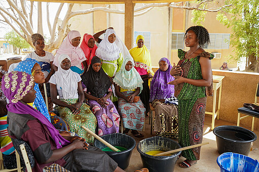 Geflüchtete Frauen in Burkina Faso bekommen eine Schulung zur Herstellung von Flüssigseife Eine Gruppe Frauen sitzt in einem Schulungsraum