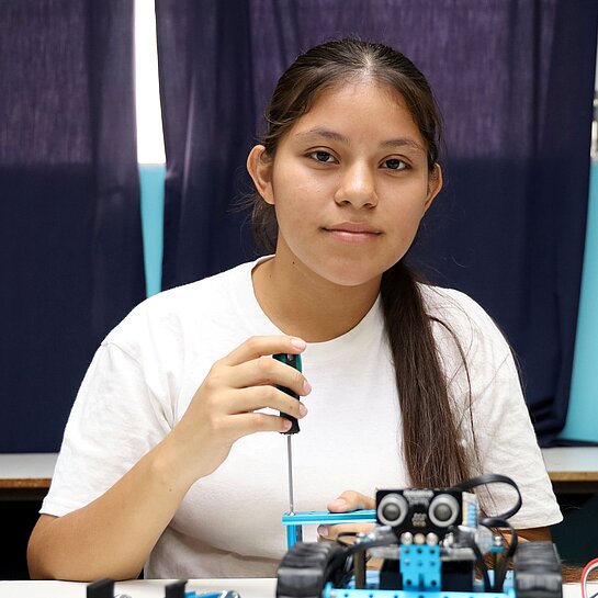 Mädchen schraubt an einem Roboter