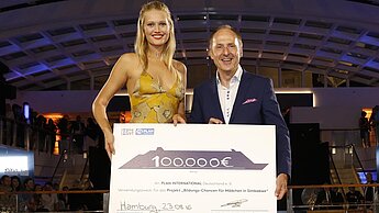 Scheckübergabe mit Plan-Botschafterin Toni Garrn: Insgesamt konnten 100.000 Euro für ein Projekt in Simbabwe gesammelt werden. © Hapag-Lloyd Cruises/Franziska Krug