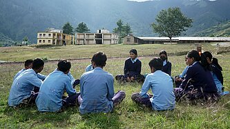 Kinder sitzen im Freien auf einer Wiese und halten ein Clubtreffen ab