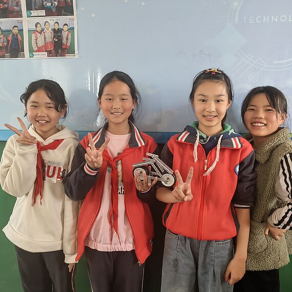 Vier Mädchen lächeln und zeigen das Peace-Zeichen