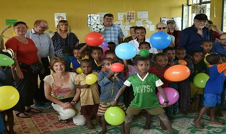 Pat:innen und Schulklasse halten Luftballons.