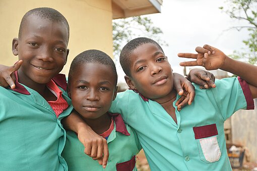 Jungen in einer von Plan International unterstützten Schule im kamerunischen Yaoundé Drei Jungen stehen zusammen