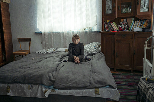 Ein Junge sitzt auf einem Bett