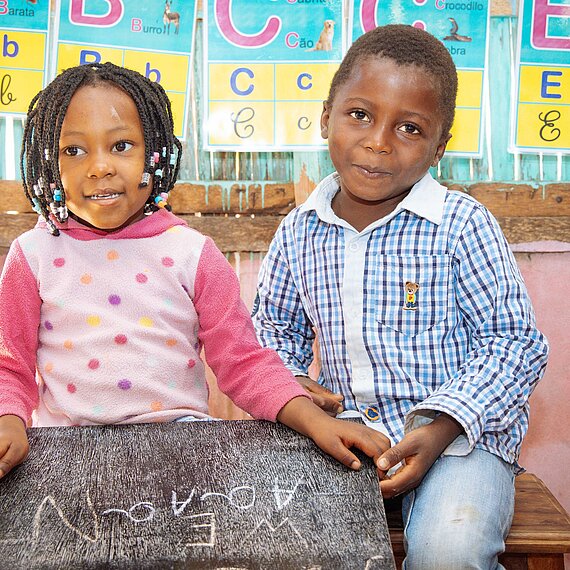 Zwei Kinder in einem Lernraum halten eine Schreibtafel in den Händen