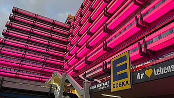 Zum Weltmädchentag 2026 ist die Edeka-Zentrale von außen in pink erleuchtet.