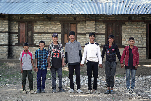 Eine Gruppe jugendlicher Jungen steht in einer Reihe und hält sich an den Händen