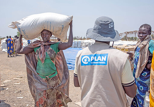 Eine Frau in Südsudan hat für sich und ihre Familie einen Sack mit Hirse erhalten Eine Frau in Afrika mit einem Sack Nahrungsmittel