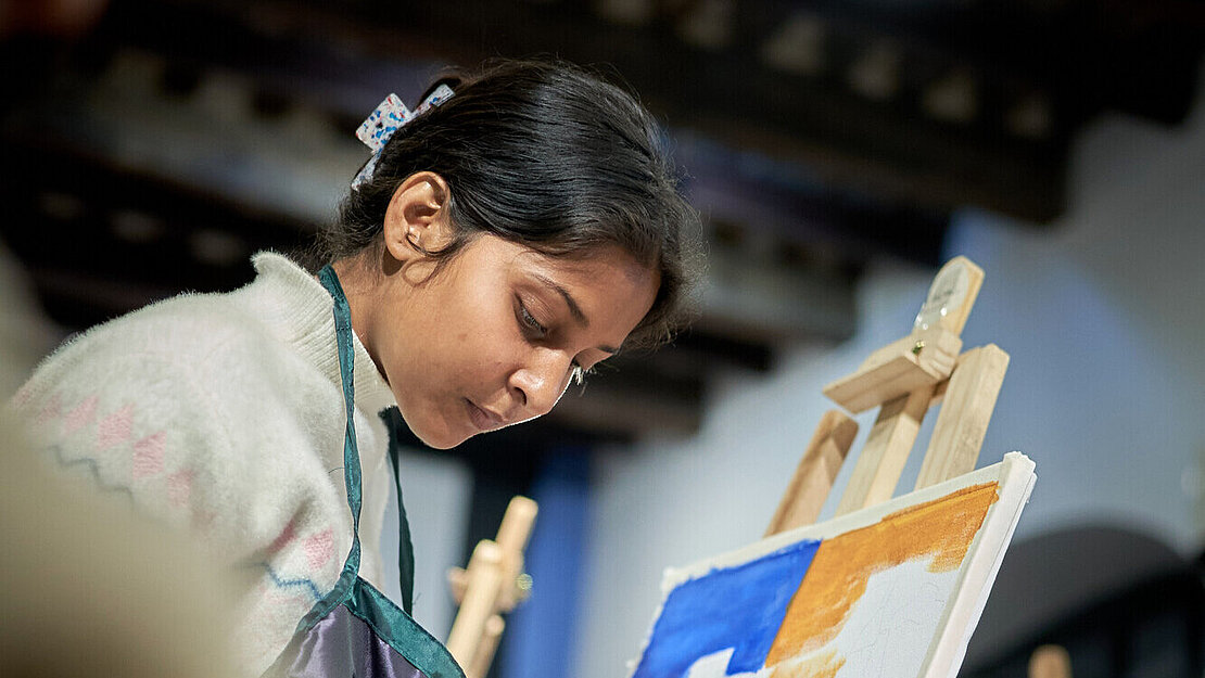 Eine junge Frau malt auf eine Leinwand