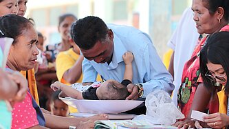 Ein Vater legt sein Baby zur Untersuchung auf eine Waage 