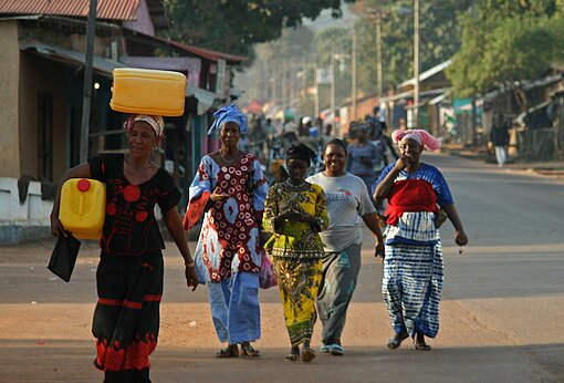 Geschäftige Straße im westafrikanischen Guinea Frauen laufen auf einer Straße