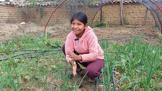 Ein Mädchen kniet auf einem Bett zwischen Zwiebeln