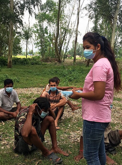 Junge Frau verteilt Masken an Wartende vor Impfzentrum