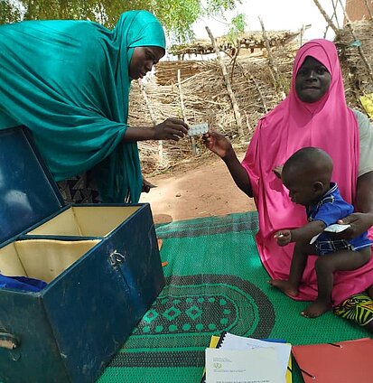 Eine Mutter mit Kind empfängt Tabletten von einer anderen Frau