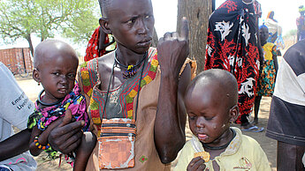 Atek wartet mit ihren beiden Kindern Lou und Amou. © Plan Atek wartet mit ihren beiden Kindern Lou und Amou. © Plan