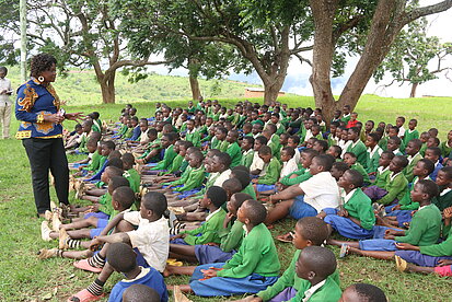 Eine Frau spricht zu einer großen Gruppe von Schüler:innen