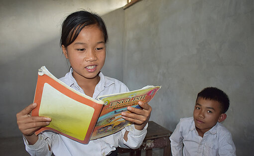 Khai und ein junge mit einem Lehrbuch in der Hand.
