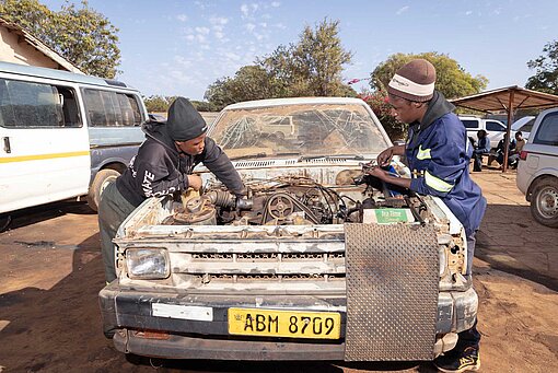 Zwei Frauen arbeiten am offenen Motorblock eines Pick-up-Wagens