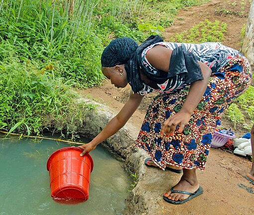 In Sierra Leone holen Frauen traditionell das Wasser Eine Frau schöpft Wasser