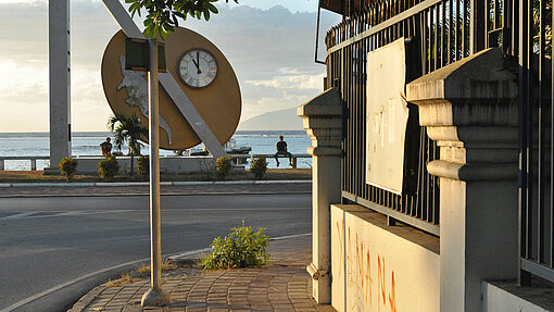 Beschaulicher Lebenswandel in Dili. Dennoch bleiben nach Einbruch der Dunkelheit viele Leute zu Hause. Abendsonne scheint auf eine Mauer am Hafen.