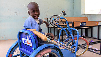 Ein Junge mit seinem neuen Dreirad-Rollstuhl in Borno, Nigeria.
