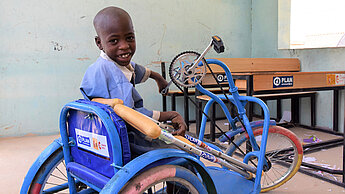 Ein Junge mit seinem neuen Dreirad-Rollstuhl in Borno, Nigeria. Ein Junge mit seinem neuen Dreirad-Rollstuhl in Borno, Nigeria.