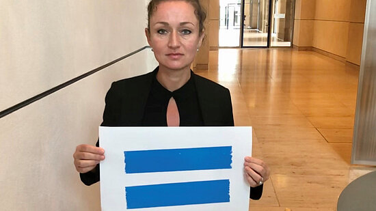 Żaklin Nastić hält ein Schild mit dem blauen Girls Get Equal Gleichzeichen hoch.