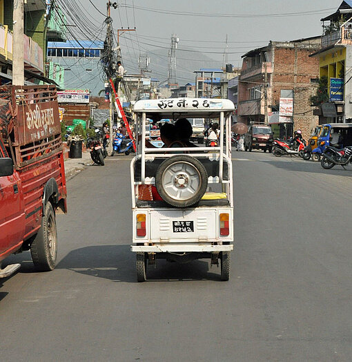 Ein nepalesisches Lasttaxi rollt durch eine Kleinstadt im Süden Nepals Ein nepalesisches Lasttaxi rollt nahe der Grenze zu Indien über dunklen Asphalt
