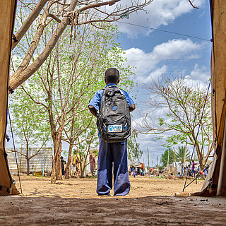 Ein Junge steht in einem Zelt in einem Campt für geflüchtete Menschen in Sudan