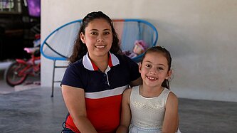 Ein kleines Mädchen und ihre Mutter sitzen auf der Veranda