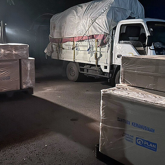 Ein Lastwagen mit Hilfsgütern, davor stehen weitere große Kartons mit Hilfsgütern