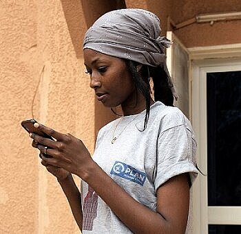Eine junge Frau aus Äthiopien hält ein Smartphone in beiden Händen und schaut darauf
