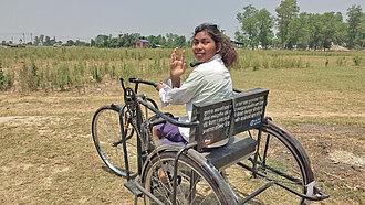 Ein Mädchen in Nepal sitzt in einem dreirädrigen Rollstuhl