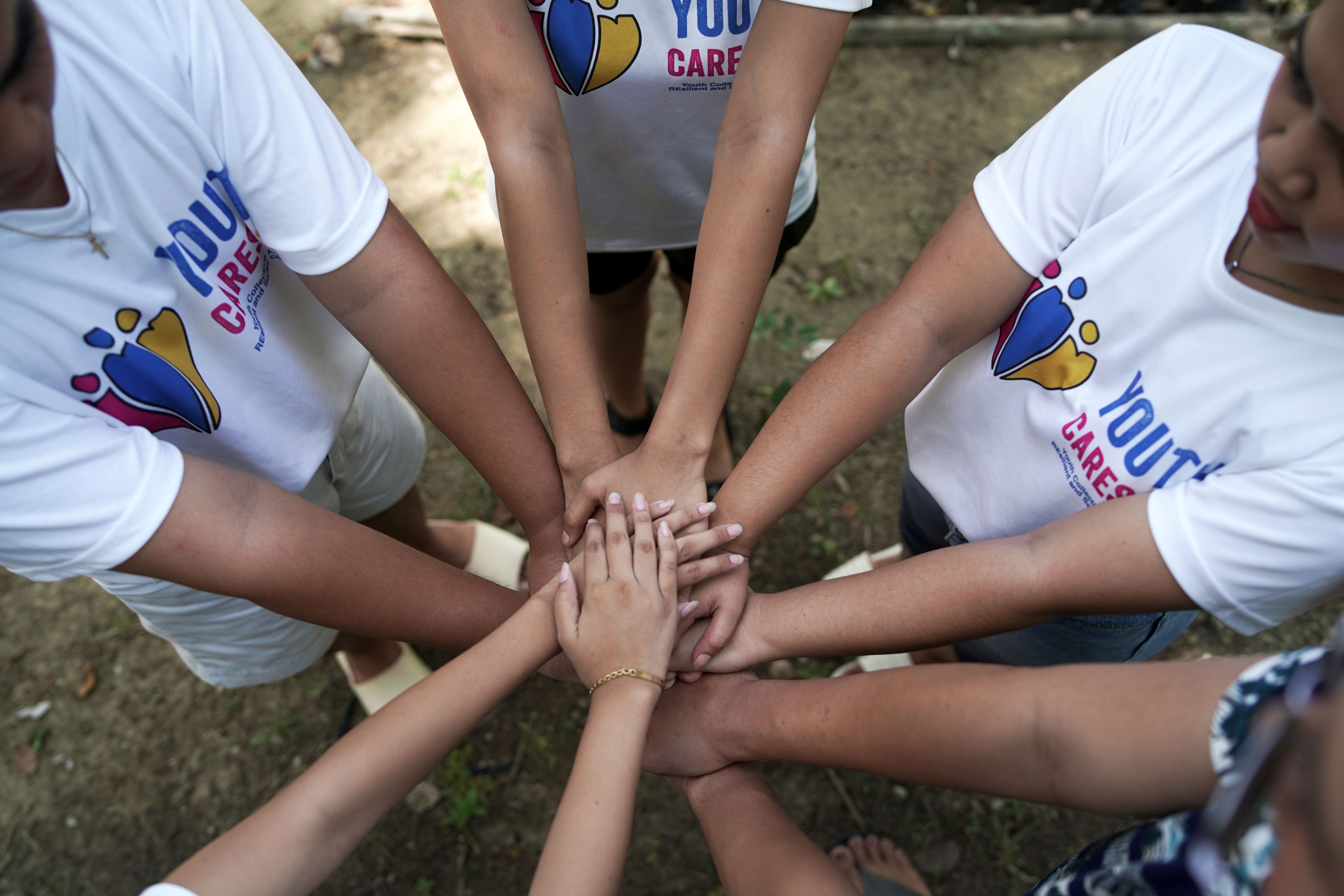 Eine Gruppe von Mädchen steht im Kreis und hat ihre Arme in die Mitte gestreckt und hält ihre Hände übereinander.